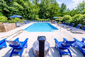 a swimming pool with blue chaise lounge chairs and a fire pit
